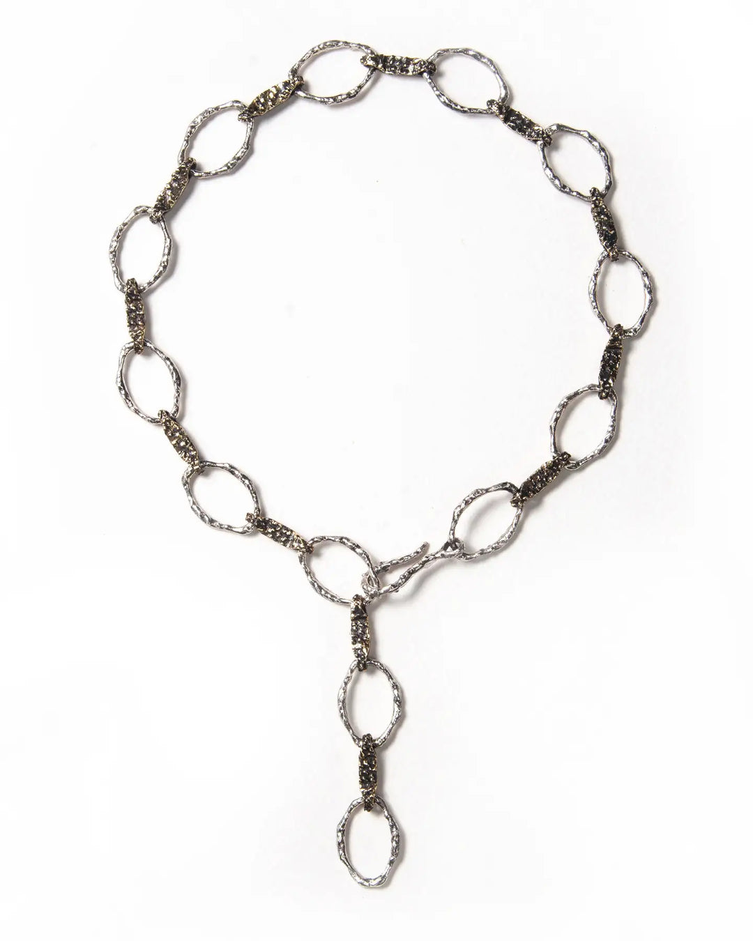 A handmade chain necklace from Naples, Italy, with a molten, textured finish. Features a versatile hook closure for wearing as a choker and can be personalized with charms using shackle clasps. Exudes timeless charm.