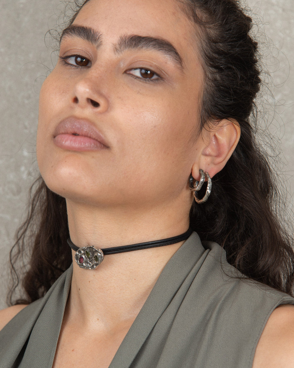 Woman wearing a black leather choker styled with a fashionable look and hoop earrings