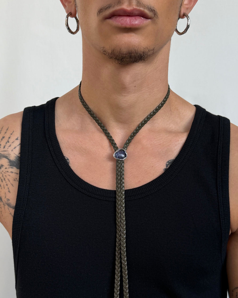 Man wearing a silver and leather necklace with a pendant