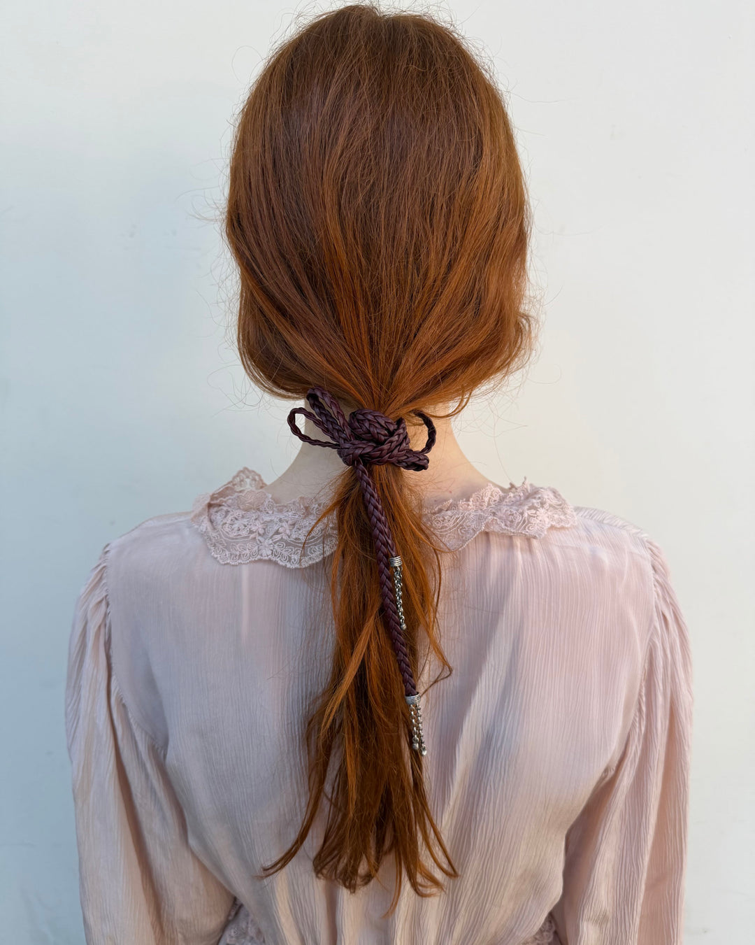 long hair tied back with a decorative ribbon