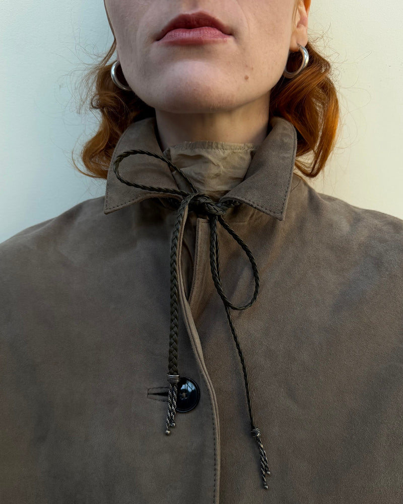Close-up of a woman wearing a suede coat with a leather and silver tie around the neck