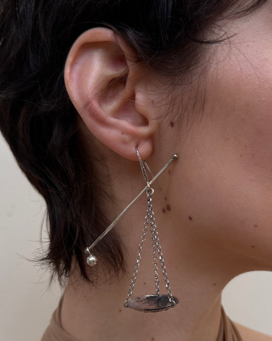 Close-up of a woman wearing a unique earring with a chain design.