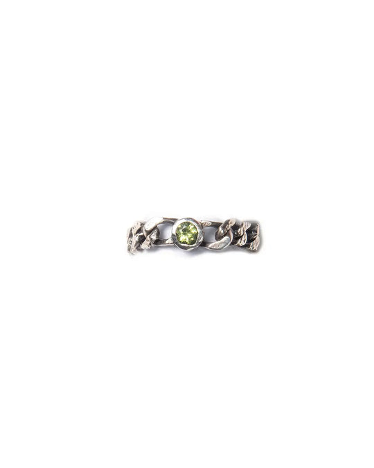 A silver ring with a chain design with a central green peridot gemstone