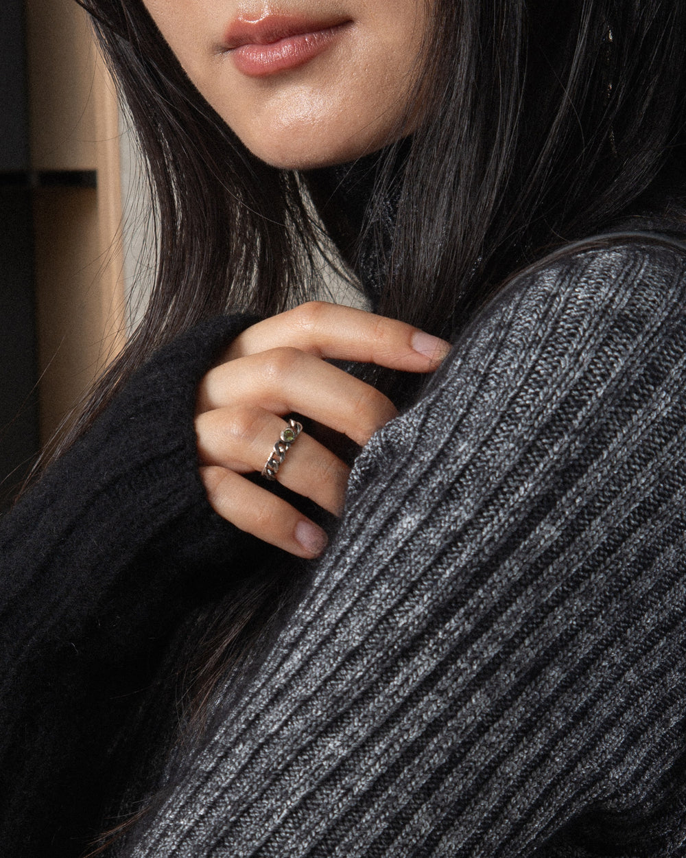 A soft chain ring with a green stone styled in the middle of the ring finger