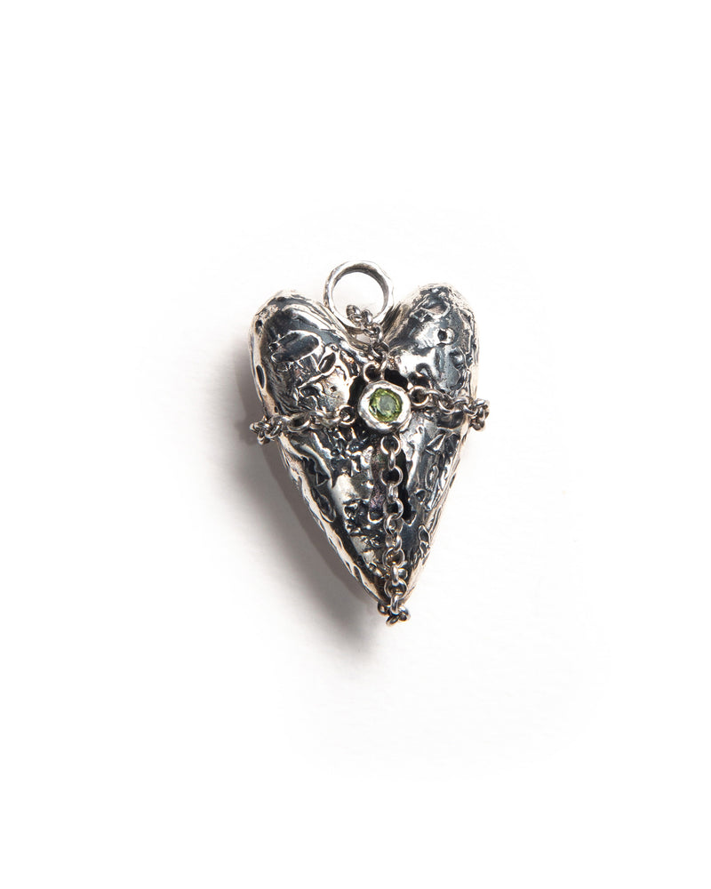 3D silver love charm with textured finish, featuring a locket-style opening, wrapped in a silver chain forming a cross pattern with a central gemstone. Stylish jewelry accessory with intricate design and layered metal details.