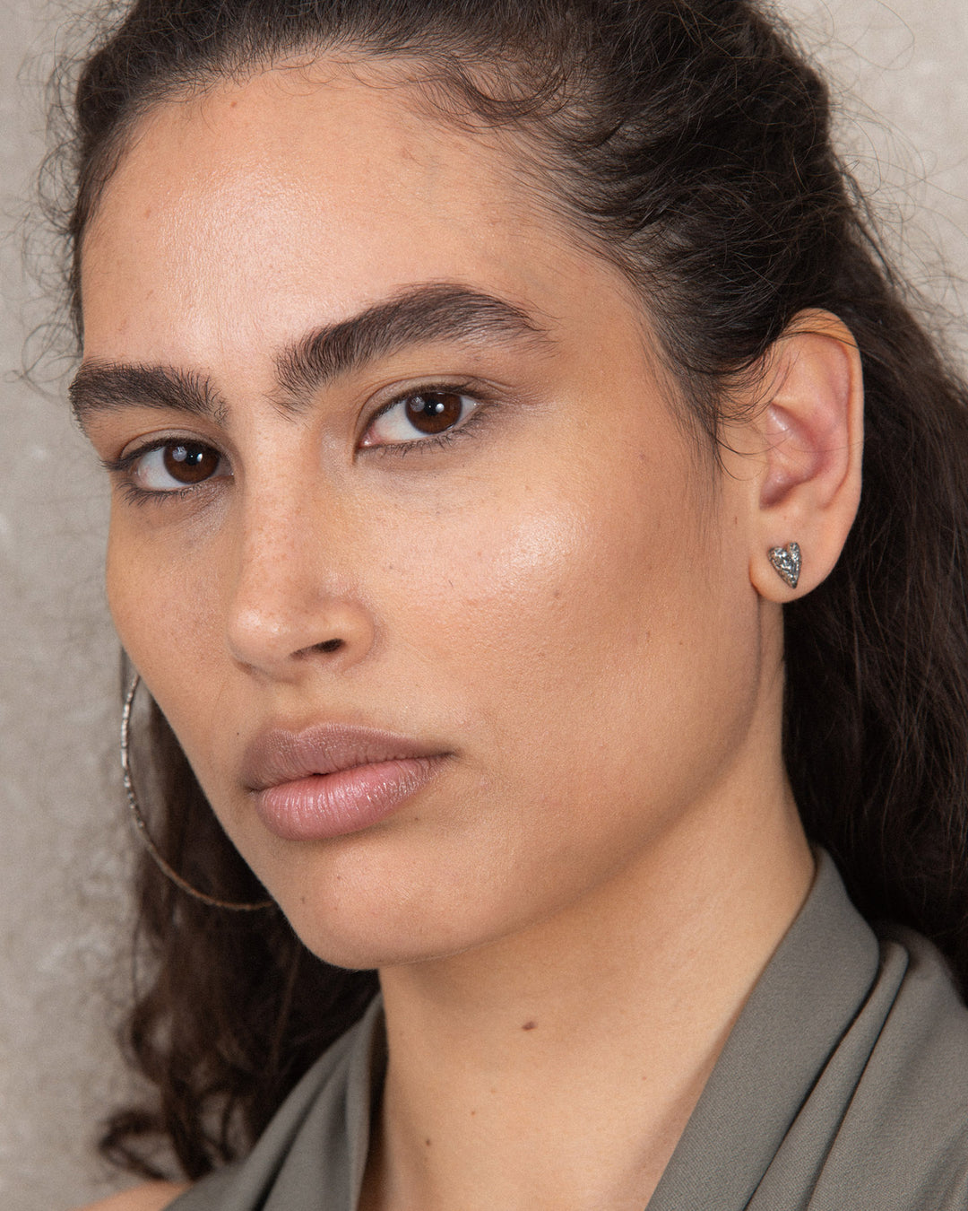 Minimalist silver heart-shaped stud earring with a subtle textured finish, showcasing a simple yet distinctive design suitable for everyday wear