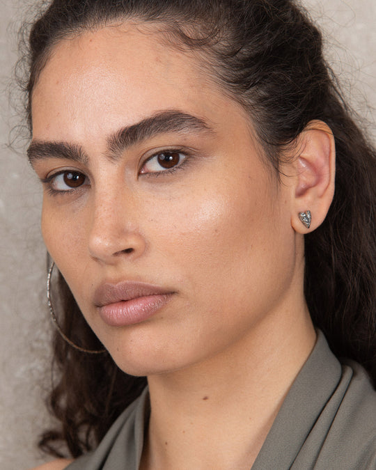 Minimalist silver heart-shaped stud earring with a subtle textured finish, showcasing a simple yet distinctive design suitable for everyday wear
