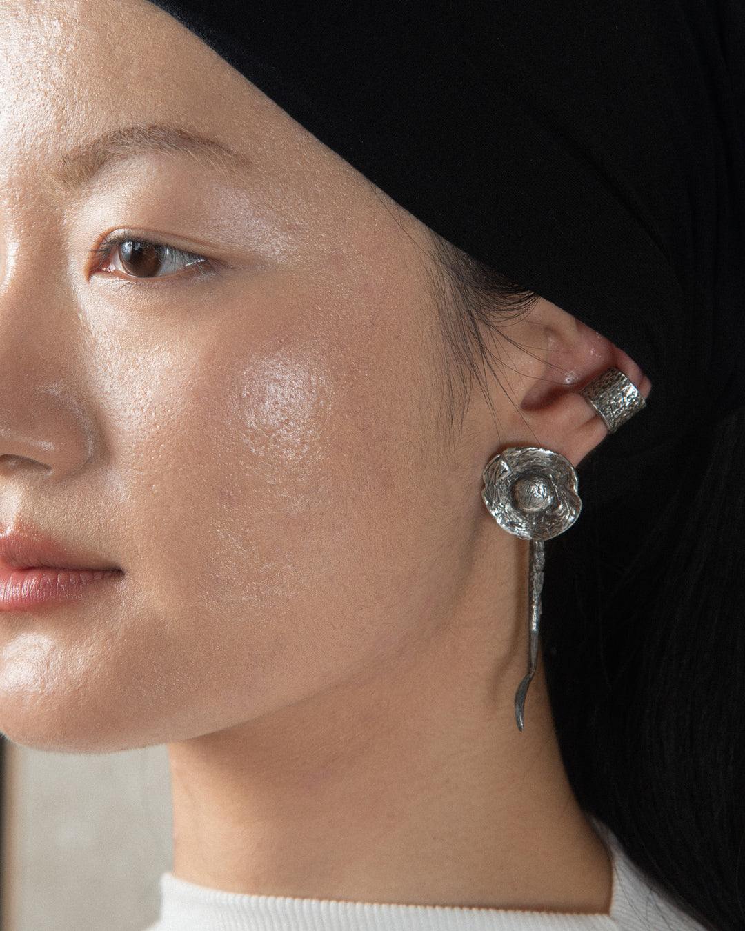 A woman wearing a silver ear cuff with a handmade finish and a mushroom-shaped earring, handcrafted in Naples, Italy.