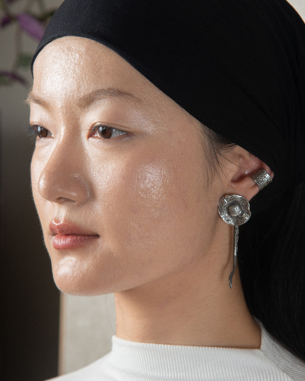 Silver fungo ear jewel with an earthy, textured finish, styled on a beautiful and sophisticated model, highlighting its natural elegance and organic design.