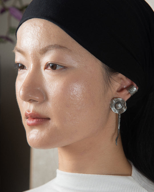 Silver fungo ear jewel with an earthy, textured finish, styled on a beautiful and sophisticated model, highlighting its natural elegance and organic design.