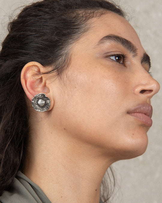 Woman wearing the flower earring, featuring its earthy, textured finish and organic design, highlighting a delicate and sophisticated accessory that complements her style.
