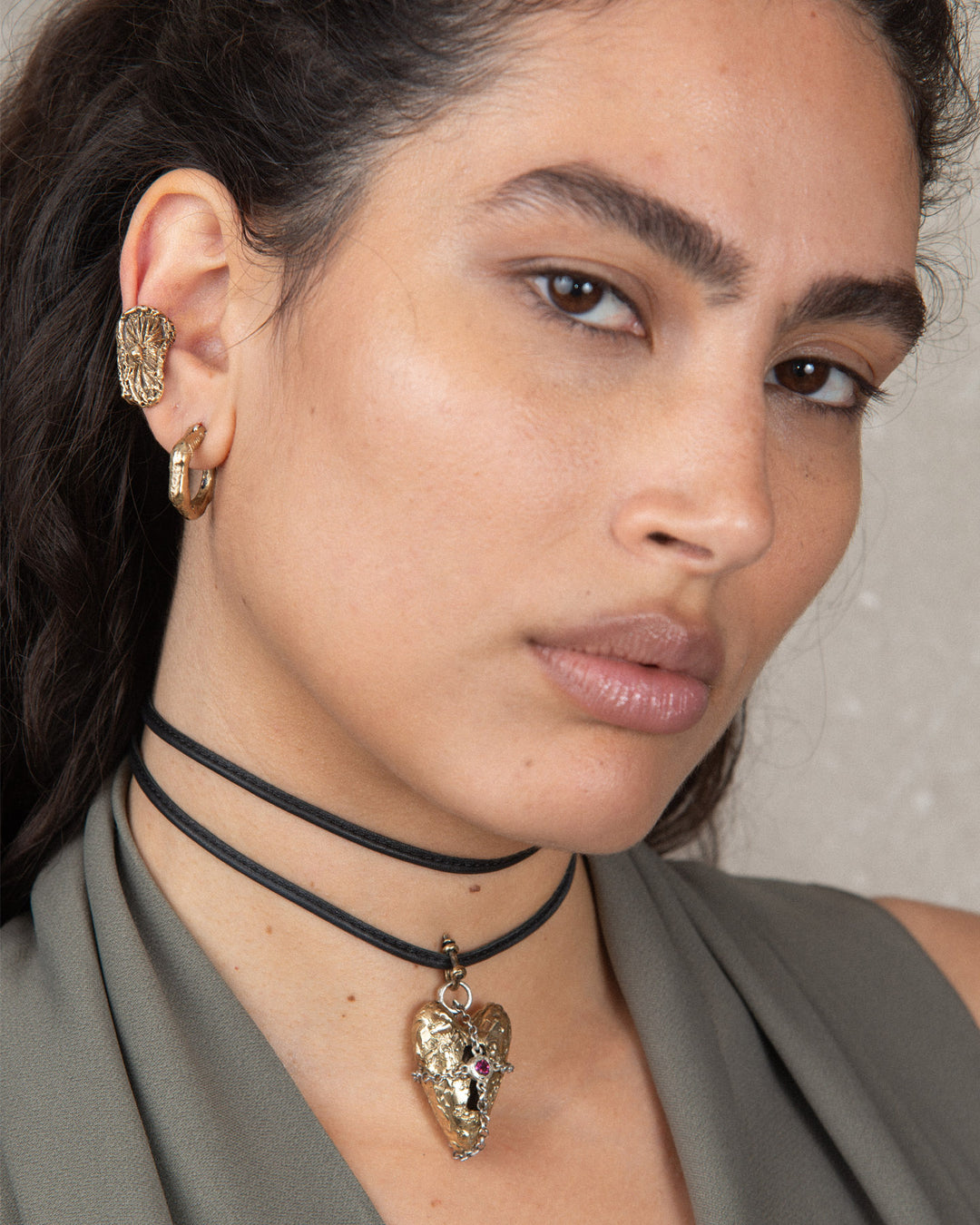 Stylish ensemble with multiple jewellery pieces including textured bronze ear cuff, earring hoops and heart choker pendant.