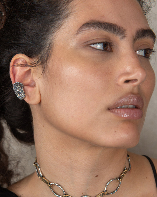 A uniquely crafted silver earring, featuring intricate details and artisanal design, adding a touch of modern elegance to any look.