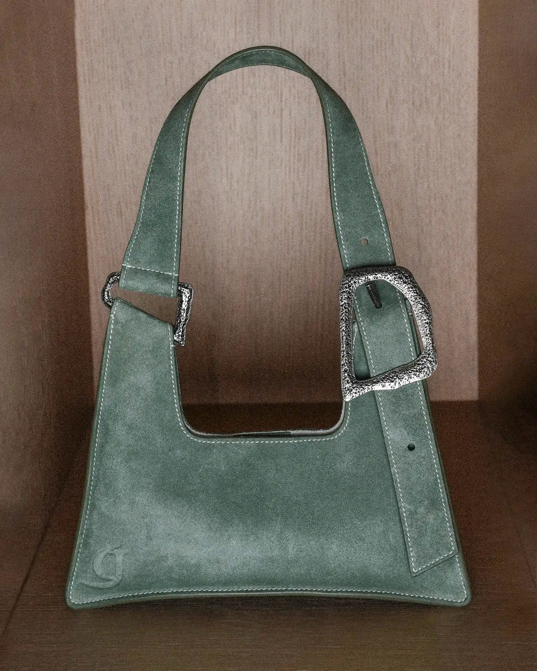 Sage green handbag with a statement buckle and adjustable handle