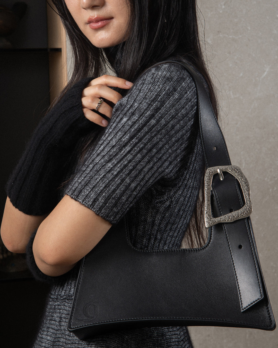 The woman wearing the luxurious bag with the silver buckle on her shoulder, showcasing the bag's elegant design and how it looks when carried.