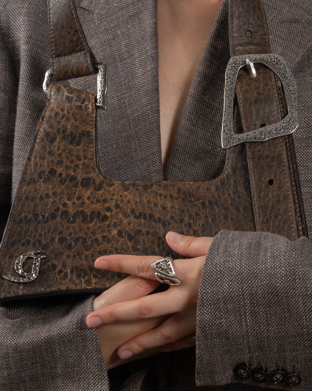 A close-up of a luxurious brown leather handbag with a crocodile-printed texture and a prominent buckle.