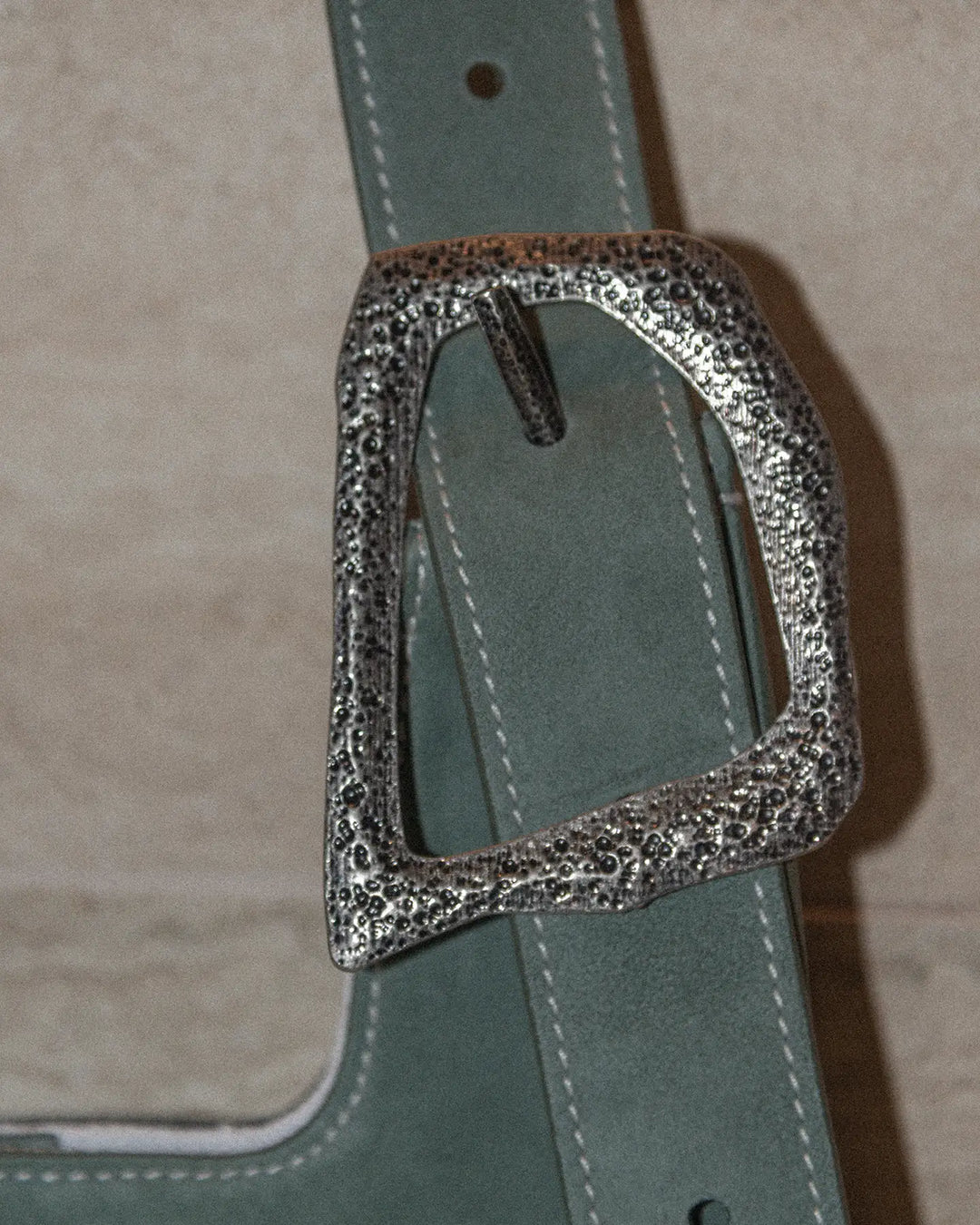 A highly detailed close-up of a handbag buckle, showcasing intricate design elements, metallic texture, and craftsmanship. The image emphasizes the shine, reflections, and fine details of the buckle for a luxurious and refined look.