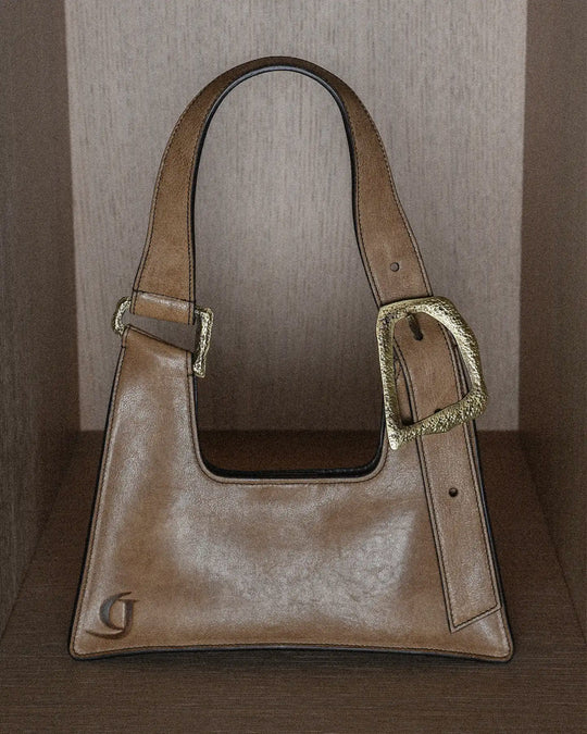 A stylish vintage-style handbag in warm tobacco hue with a rich, textured surface. The bag features classic detailing and a timeless design, perfect for adding a touch of retro sophistication to any outfit. Its aged finish and vintage texture evoke a sense of timeless elegance and effortless charm.