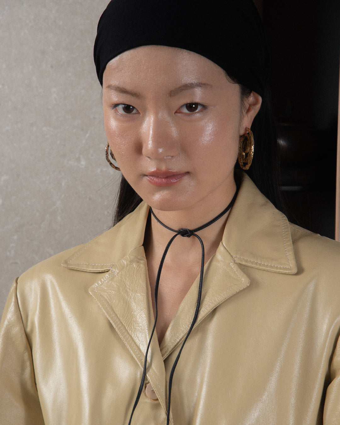 A close-up of the black leather ribbon tied in a simple, minimal knot, showcasing the sleek craftsmanship and smooth texture of the leather. The knot is subtle and elegant, emphasizing the minimalist design of the accessory.