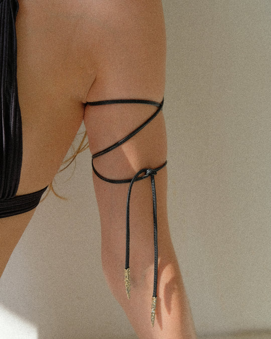 The leather ribbon, showcasing its versatility, is wrapped three times around the arm, creating a layered and stylish look.