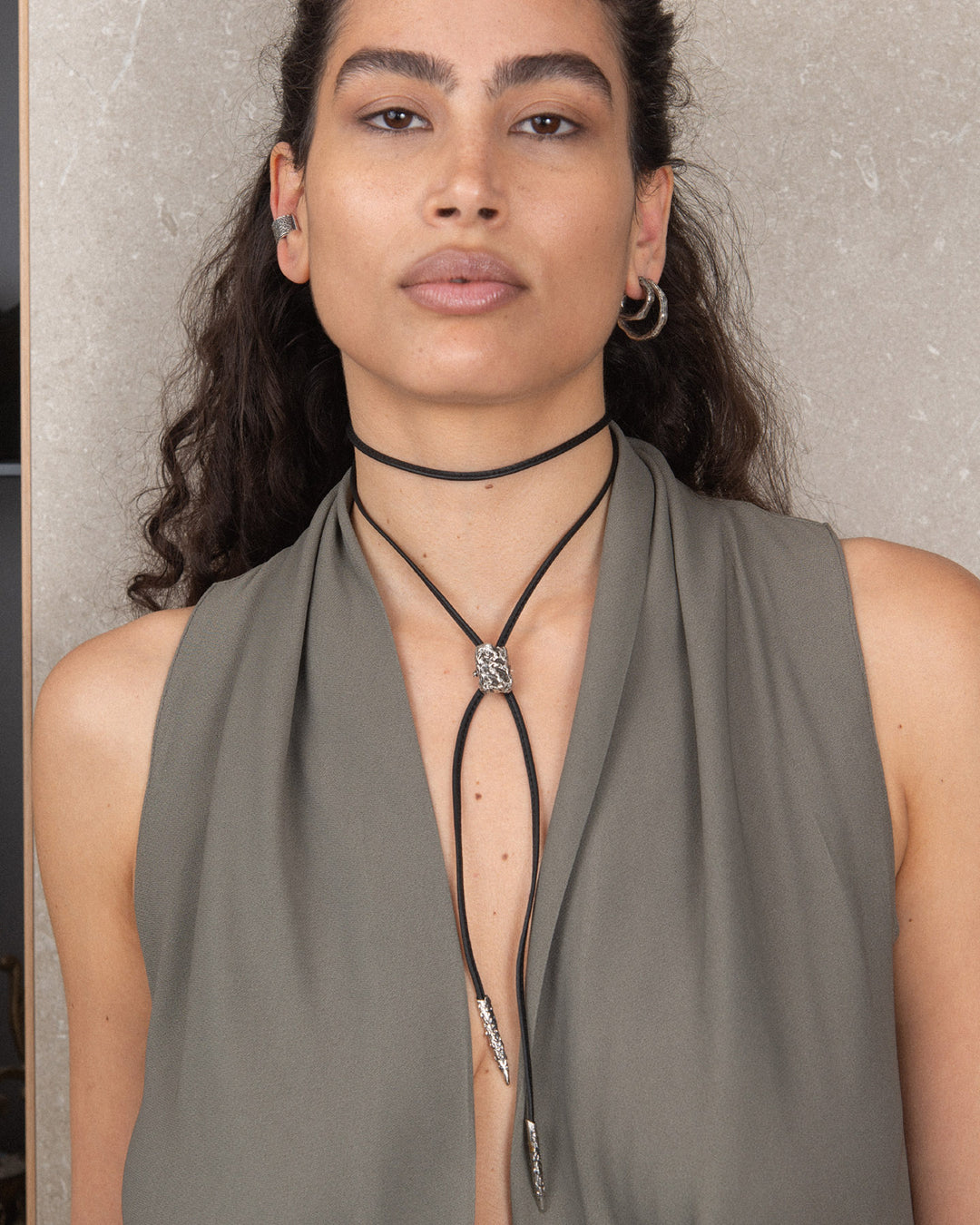 A model wearing the black leather ribbon as a choker, adorned with a textured unisex silver charm that is sleek and sophisticated. The minimalist design offers a modern and elegant look, perfect for versatile styling and customization.