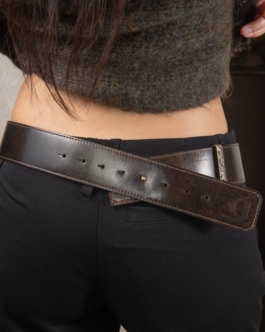 From the back, the metal belt loop and the logo pressed into the leather are visible, showcasing the craftsmanship and subtle branding details. The belt sits smoothly on her hips, emphasizing both style and quality.