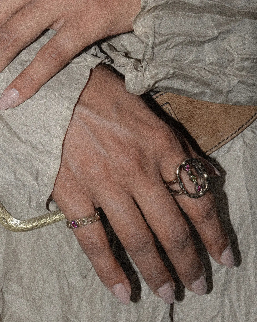 bronze chain ring with pink stone styled on the pinky finger and paired with a statement ring