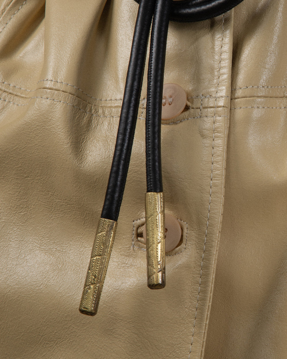 A close-up shot of the bronze metal details on the belt, highlighting the textured finish. The focus is on the intricate surface texture, showcasing the beauty of the craftsmanship
