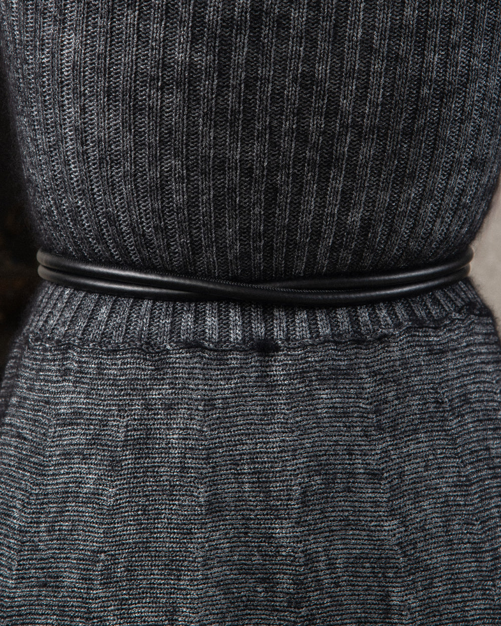 Close-up of the back side of a sleek, minimalist tubular belt in high-quality black leather. The design is streamlined and refined, emphasizing craftsmanship and elegance, showcasing smooth texture and precise craft