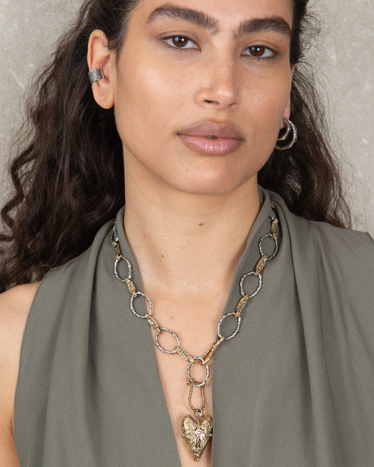 A heart pendant hooked onto a chain with a silver horseshoe-shaped clasp, showcasing a layered and customizable jewelry look.