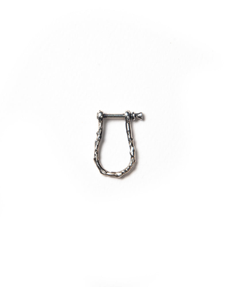 A silver clasp with a horseshoe shape and a textured surface, designed to attach charms to chains or earrings for a layered, customizable look. The clasp can also be used as an earring for people with larger piercings.