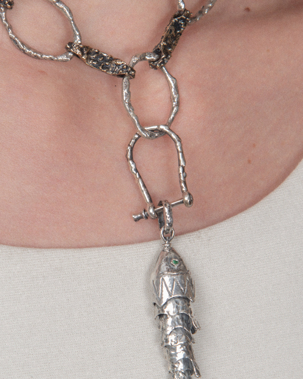 A pendant attached to a chain using a silver horseshoe-shaped clasp, allowing for a layered, customizable look.