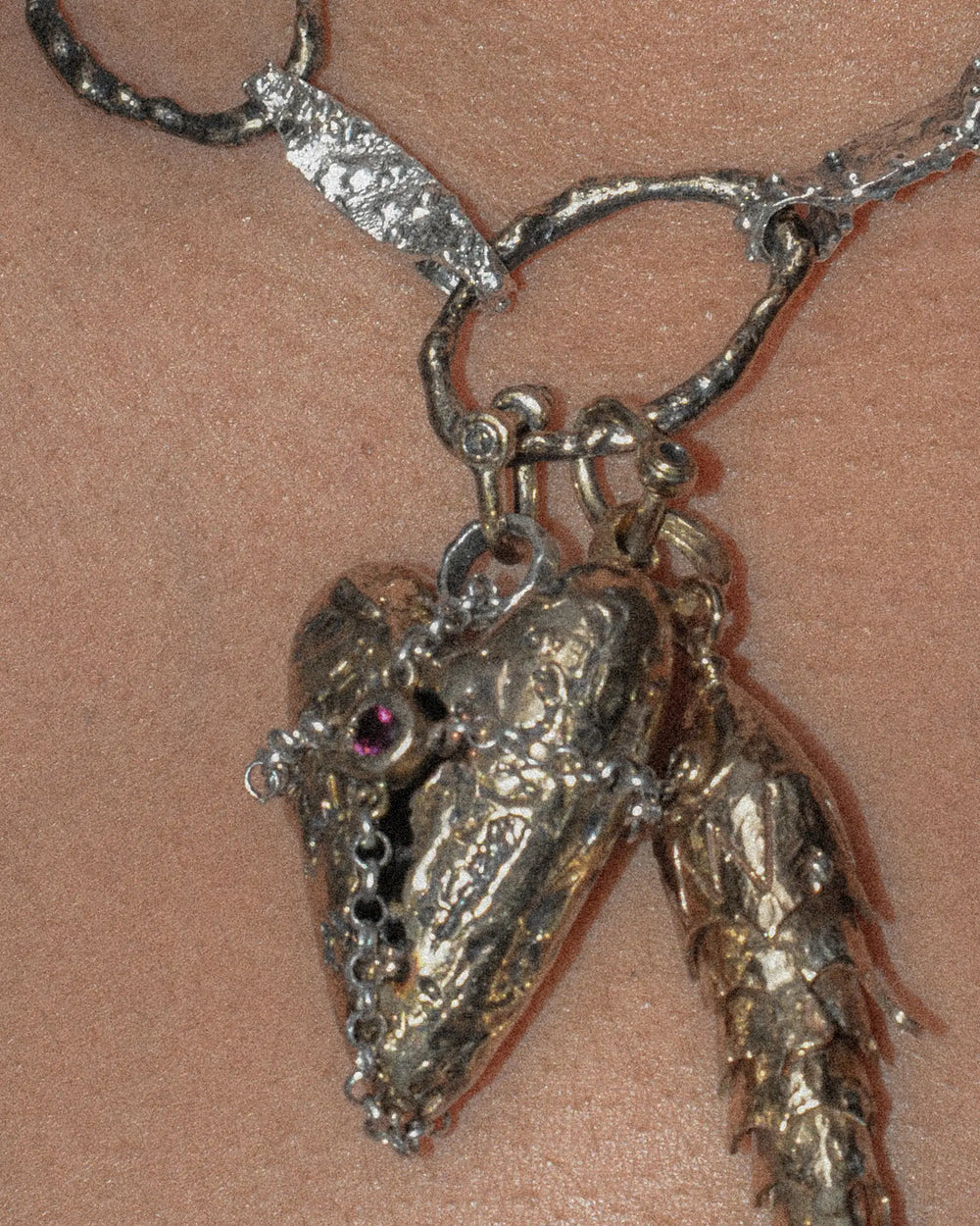 Small bronze shackle clasp used to hook a fish and heart pendant on a chain.