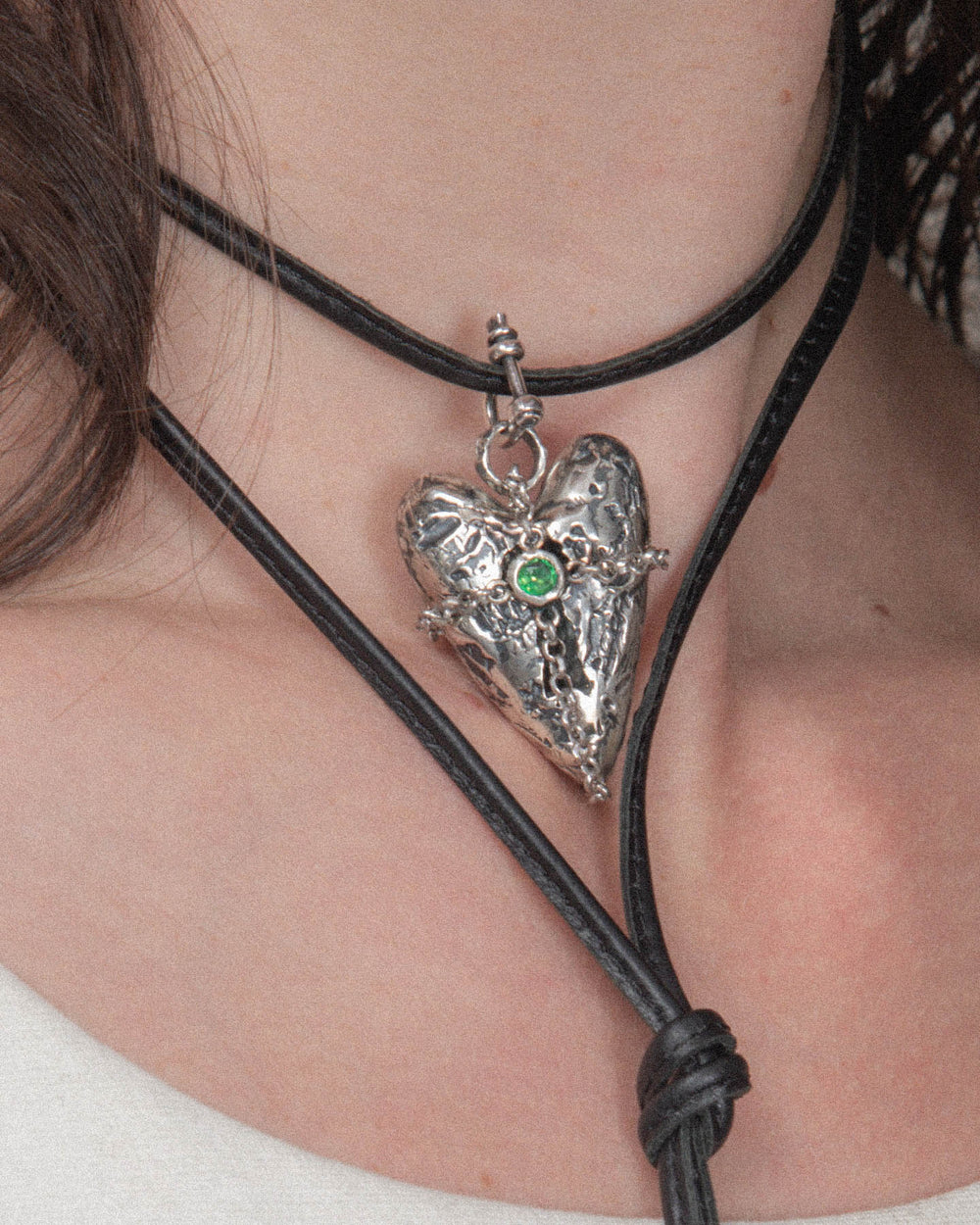 A small silver shackle clasp used to attach a heart-shaped pendant to a leather choker.