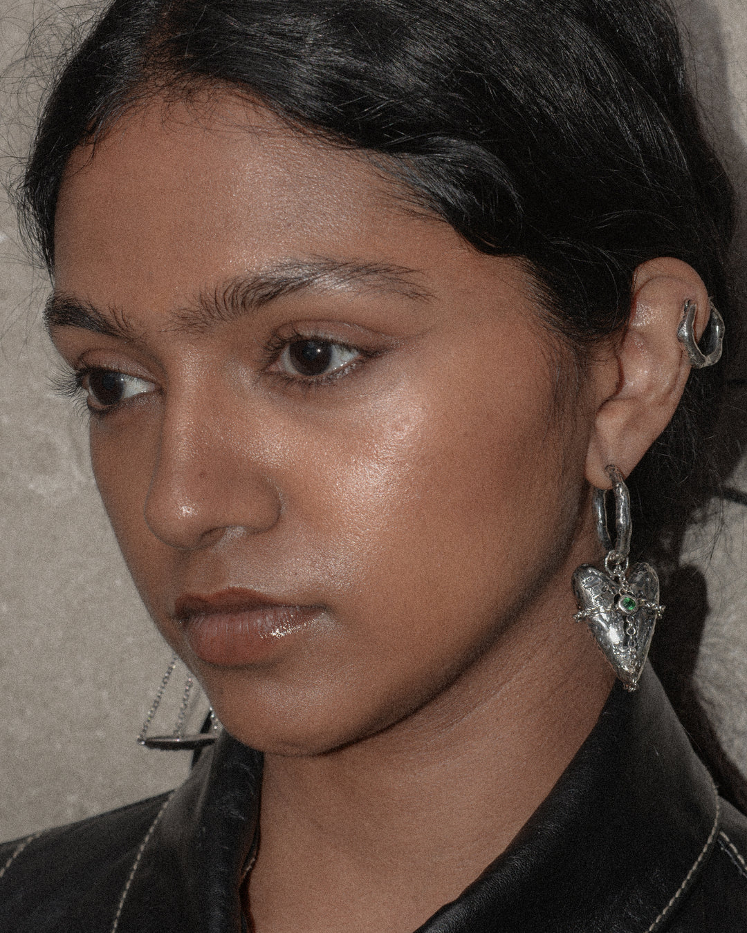A woman showcasing a personalized ear jewelry look with three refined pieces: hoop earrings, a small hoop, and a heart-shaped charm. She can layer them together or wear them separately to create a distinctive style that highlights her unique personality and versatile fashion sense.