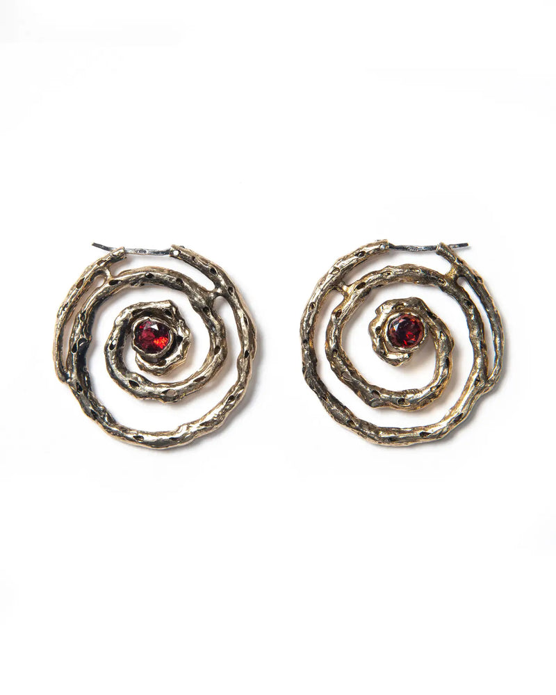 A pair of bronze hoop earrings that evoke ancient beauty, textured finish and red stones, crafted in Italy.