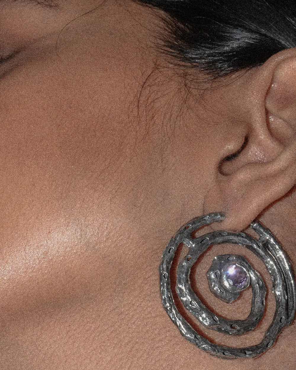 detailed view of the spiral earring with a delicate lilac gemstone sparkling