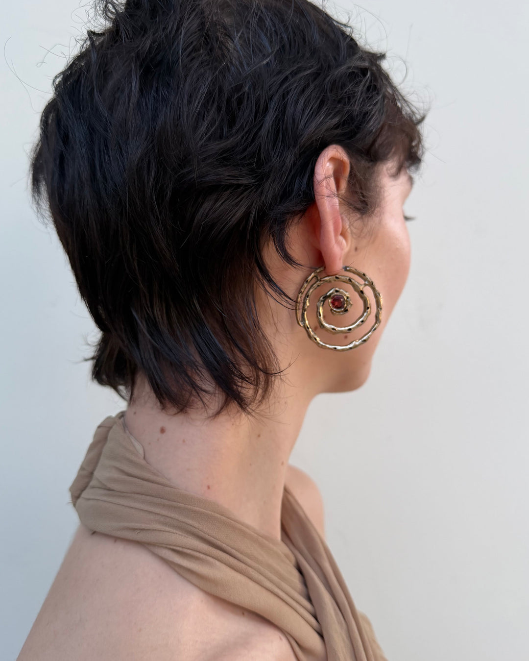 Woman with short hair wearing a large gold hoop earring