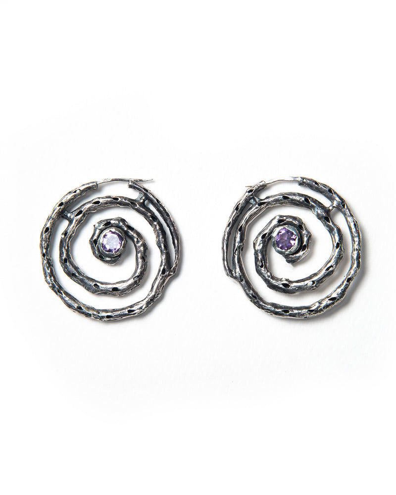 A pair of silver hoop earrings with a textured finish and purple amethyst stones, crafted in Italy.